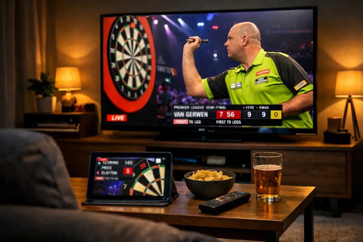 Laptop scherm met darts live stream naast een dartbord in een woonkamer